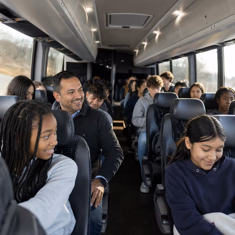 Group boarding a white charter bus for School Transportation transportation in New Orleans
